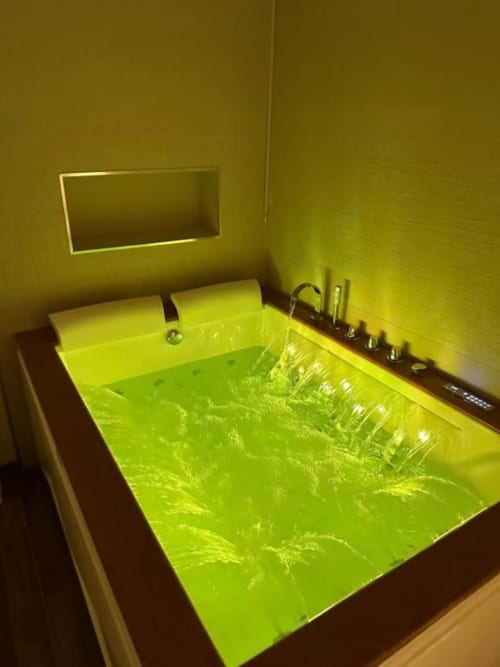 Vasca da bagno illuminata in verde neon brillante presso l'appartamento Enjoy House Bracciano, con finiture moderne