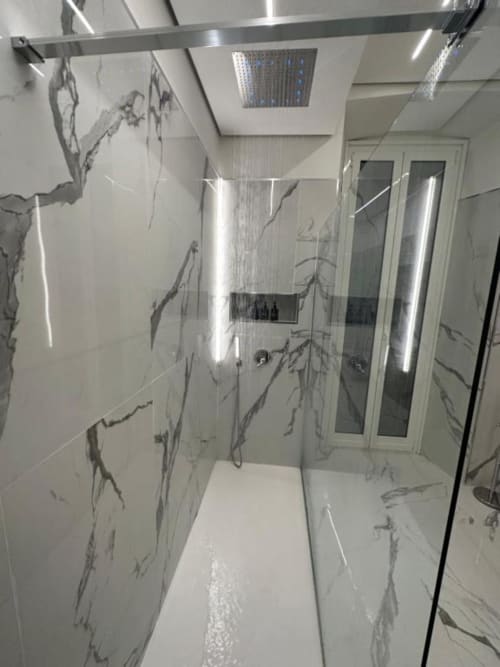 Moderno bagno con pareti effetto marmo, soffione a pioggia e box doccia in vetro presso l'appartamento Enjoy House Bracciano