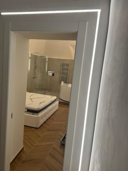 Camera da letto moderna con bagno ensuite a Enjoy House Bracciano, con porta bianca e pavimento a spina di pesce