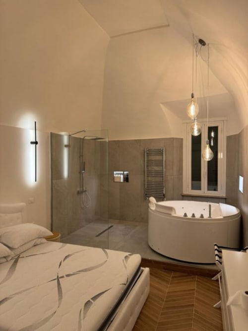 Lussuoso bagno di Enjoy House Bracciano con vasca idromassaggio angolare, doccia walk-in, lampade a sospensione e vista sulla camera