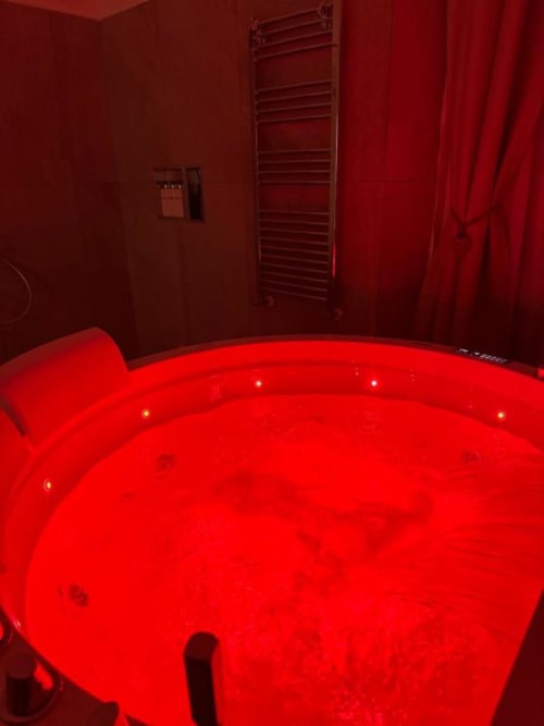 Vasca idromassaggio con illuminazione rossa nel bagno dell'appartamento Enjoy House Bracciano, con getti illuminati e portasciugamani