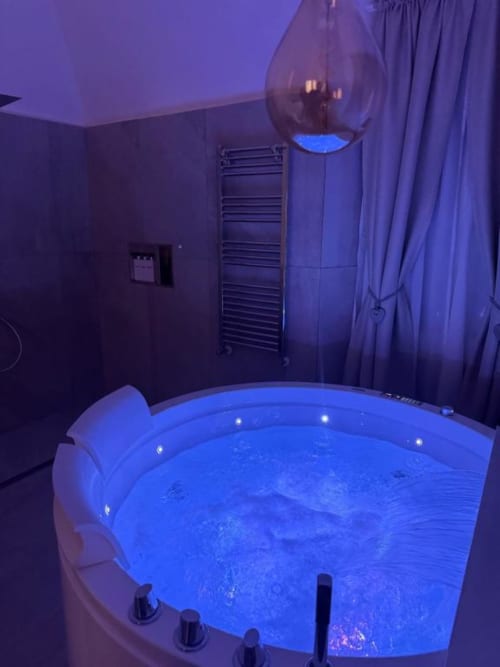 Vasca idromassaggio moderna con illuminazione LED blu nella lussuosa residenza di Bracciano, con lampade ambientali viola e finiture cromate