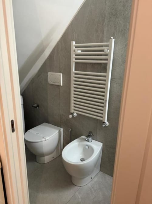 Bagno moderno in Enjoy House Bracciano con toilette, bidet, portasciugamani bianco e piastrelle scure