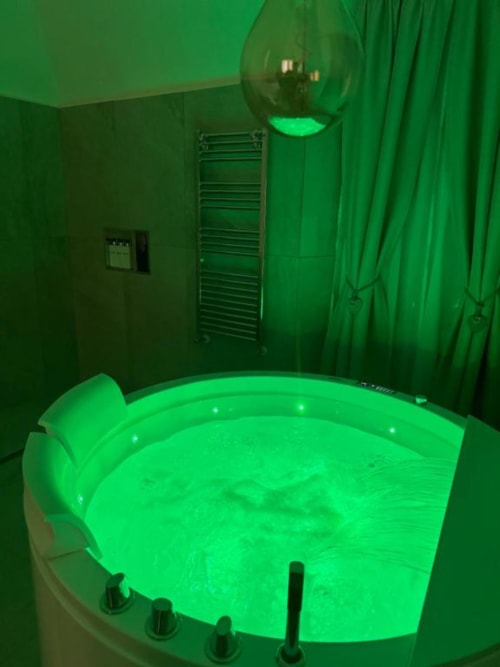 Vasca idromassaggio luminosa verde acido nel moderno bagno di Enjoy House Bracciano con illuminazione ambientale e comandi idrogetti