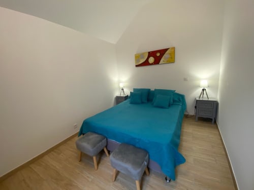Chambre moderne du Domaine du Bez avec literie turquoise, lampes jumelées et parquet à Saint Laurent d'Olt
