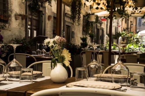 Elegante allestimento per cena all'aperto presso Enjoy House Bracciano con fiori bianchi, mise en place e suggestivo cortile italiano