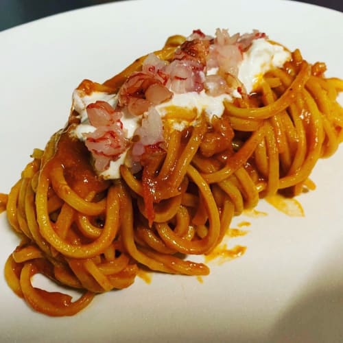 Piatto di pasta al sugo di pomodoro, noodles croccanti, cipolla tritata e guarnizione cremosa all'Enjoy House di Bracciano