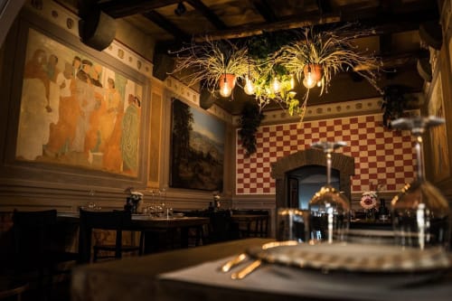 Elegante sala da pranzo di Enjoy House Bracciano con affreschi rinascimentali, pareti scacchiere e illuminazione ambientale per la cucina raffinata