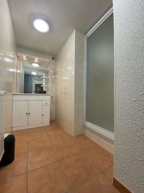Salle de bains moderne avec vasque blanche, carrelage terre cuite et douche vitrée au gîte Le Domaine du Bez