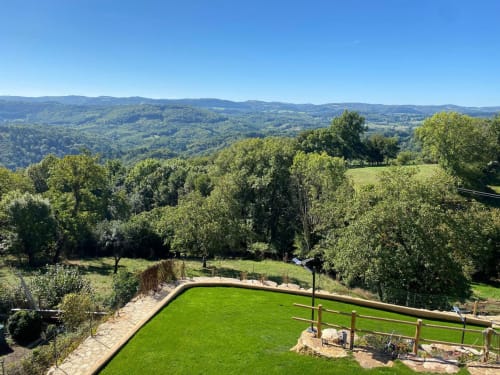 Le jardin champêtre du Domaine du Bez surplombant une verdoyante vallée et les montagnes lointaines de Saint Laurent d'Olt