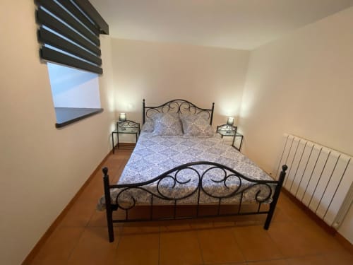 Chambre douillette du gîte Le Domaine du Bez avec lit en fer forgé, vue sur les montagnes et carrelage en terre cuite