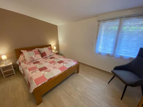 Chambre de la maison d'hôtes Le Domaine du Bez à Saint Laurent d'Olt avec lit en bois, literie matelassée rose et vue sur les montagnes