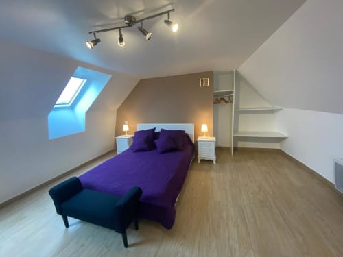 Chambre mansardée moderne au gîte Le Domaine du Bez avec literie violette, puits de lumière, tables de nuit blanches et parquet