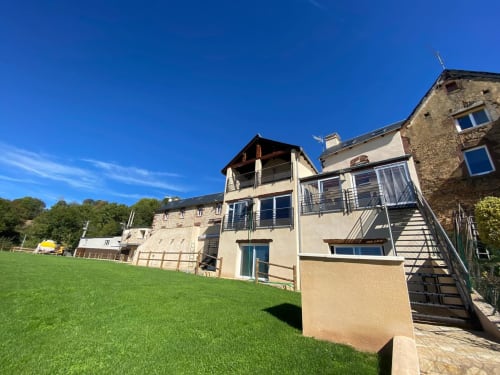 Cottage du Domaine du Bez avec vue montagne, pelouse verdoyante et architecture en pierre à Saint Laurent d'Olt