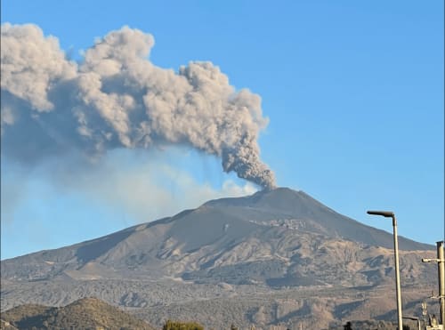 L'Etna in eruzione con pennacchio di cenere vulcanica sopra Catania, Sicilia, vista da Tagasuites
