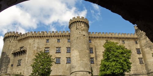 Facciata del Castello di Bracciano con torri in pietra e merlature, incorniciata da arco, Bracciano Italia