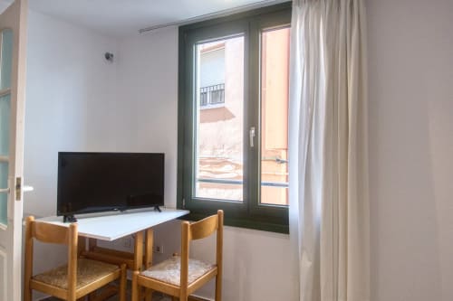 Cozy studio apartment in Palafrugell with TV, wooden chairs, and glass doors opening to beachfront balcony view