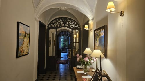 Élégant couloir de la Chambre d'hôtes La Cordeline à Brignoles avec plafond voûté, portes noires, tableaux encadrés et fleurs fraîches