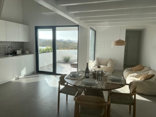 Área de estar da villa Casa Zavial com cozinha, mesa de jantar e terraço com vista para o mar em Bordeira, Portugal