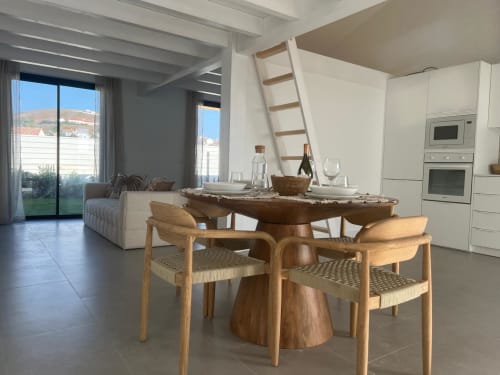Sala de jantar moderna na villa Casa Zavial com mesa de madeira, cadeiras, cozinha e vistas para o mar em Bordeira, Portugal