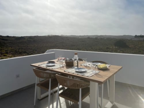 Área de refeições na cobertura da villa Casa Zavial em Bordeira com mesa posta para dois com vista para a paisagem costeira