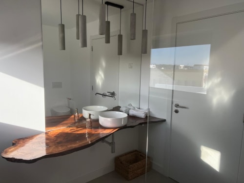 Banheiro moderno da villa Casa Zavial com duplas pias redondas, bancada em madeira natural, iluminação pendente e vista para o mar