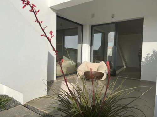 Terraço da moderna vila Casa Zavial em Bordeira com vista para o mar, mobiliário contemporâneo e flores vermelhas vibrantes
