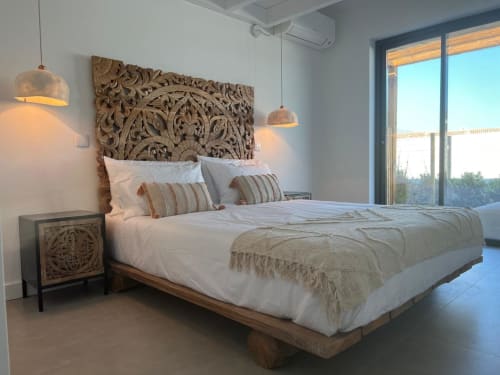 Luxury bedroom in Casa Barranco villa with carved wooden headboard, pendant lights, and sea view from private balcony in