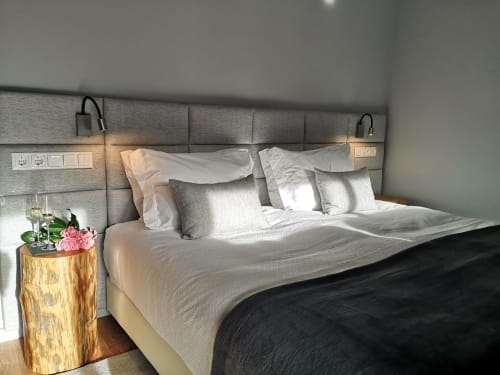 Quarto moderno da villa de montanha Em Xisto em Góis com cabeceira estofada cinzenta, roupa de cama branca e mesa de cabeceira de madeira com