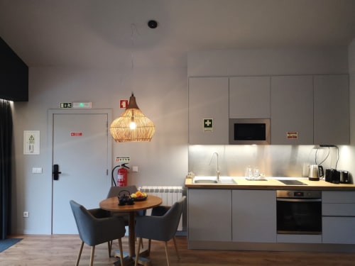 Cozinha e sala de jantar modernas da villa Em Xisto na serra de Góis, com iluminação pendente, armários cinzentos e mesa de madeira