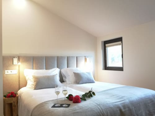 Quarto moderno na casa de montanha Em Xisto, Góis Portugal, com cabeceira cinzenta, roupa de cama branca e janela com vista para a montanha