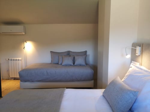Quarto moderno com camas duplas no hotel Em Xisto em Góis, Portugal, com roupa de cama azul, paredes brancas e vistas para a montanha