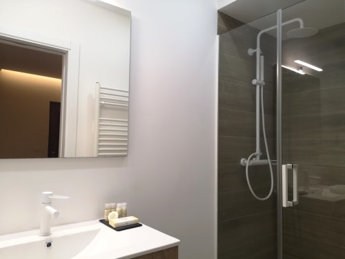 Casa de banho moderna na moradia East Schist House do hotel Em Xisto, Góis, com lavatório branco, espelho e chuveiro tipo chuva com vidro