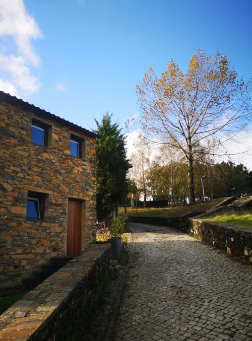 Casarão de pedra na pousada Em Xisto, Góis, Portugal, com árvores de outono e caminho de paralelepípedos