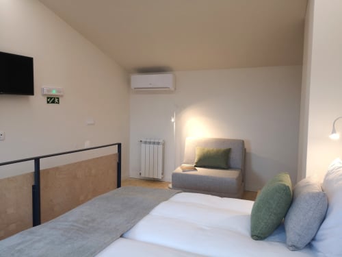 Quarto moderno do hotel Em Xisto em Góis com cama, poltrona, ar condicionado e vista para a serra com luz natural