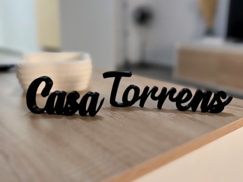 Letrero negro Casa Torrens sobre superficie de madera con fondo de cocina desenfocado