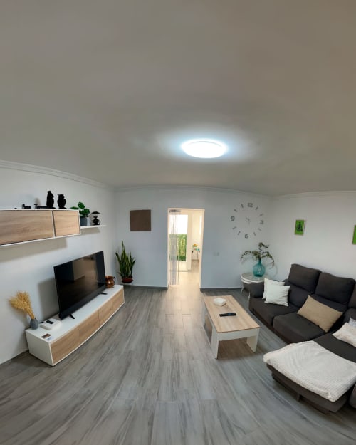 Sala moderna del apartamento Casa Torrens Mar y Montaña en Polop de la Marina con sofá negro, televisión y muebles de madera