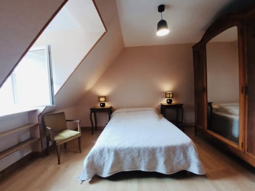 Chambre lumineuse sous les combles à la Conciergerie Pour Tous, cottage de Corrèze avec lit blanc, poutres bois et lumière naturelle