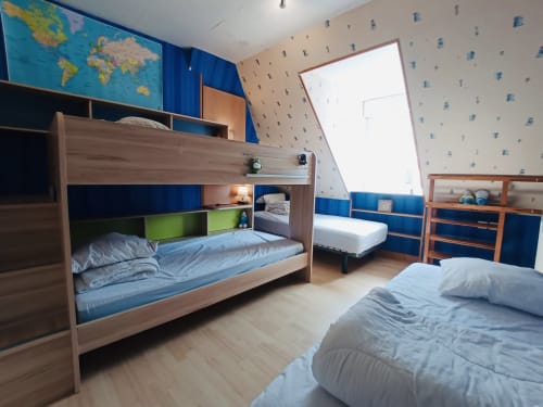 Chambre familiale spacieuse du gîte corrézien avec lits superposés, lit simple, mappemonde et accents bleus