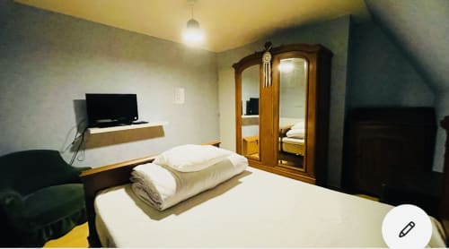 Chambre douillette avec draps blancs, armoire en bois, TV et vue sur le jardin dans les Bois de Corrèze