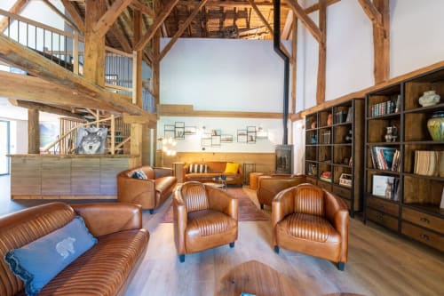 Salon rustique du chalet avec sièges en cuir, poutres apparentes, cheminée et vue sur les montagnes au Domaine de l'Epigny
