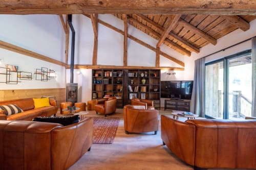 Salon de chalet de luxe avec sièges en cuir cognac, poutres apparentes, cheminée et vue montagne au Domaine de