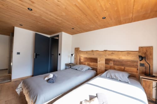 Chambre cozy du Chalet de L'Epigny avec deux lits en bois, vue sur les montagnes, murs blancs modernes et plafond en bois à Grand