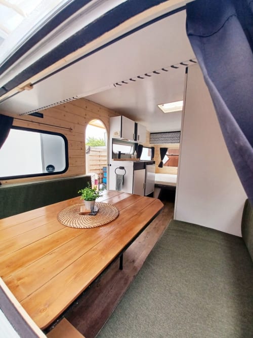 Intérieur cosy du cottage La Cour d'Hortense avec table en bois, kitchenette et vue sur le jardin à Sailly-Flibeaucourt