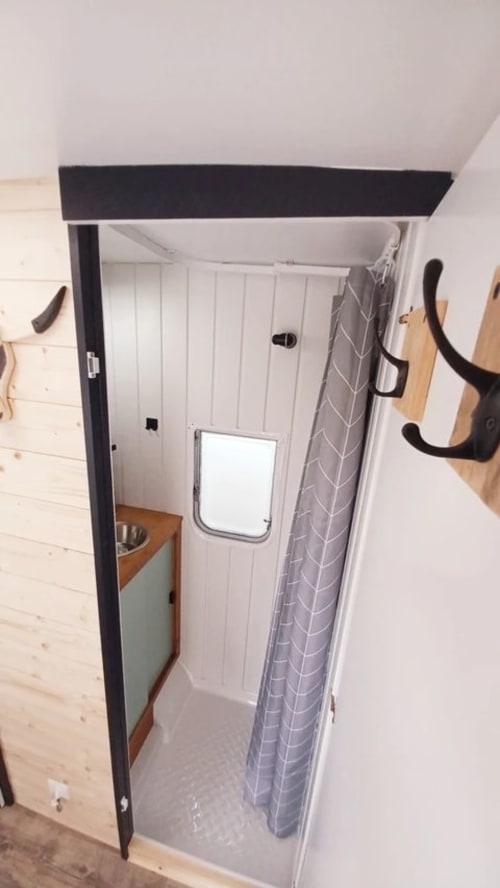 Petite douche dans le cottage La Cour d'Hortense aux murs blancs et rideau gris