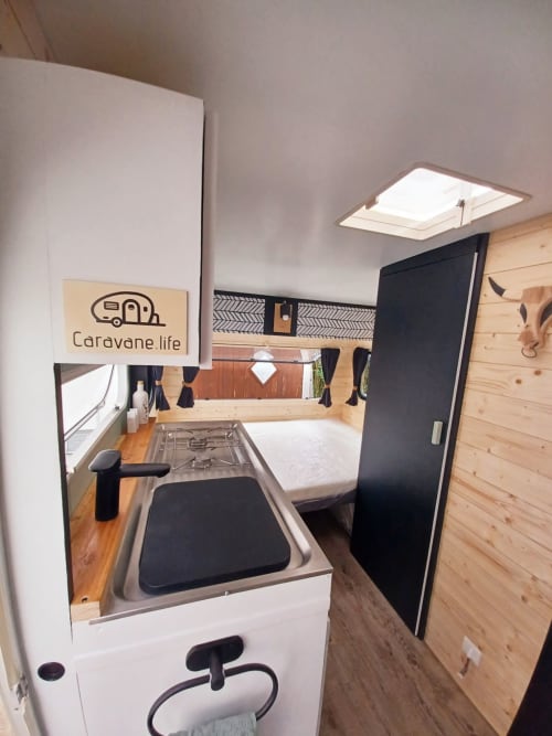 Cuisine compacte de caravane avec cuisinière à gaz, évier et intérieur en bois au gîte La Cour d'Hortense, Sailly-Flibeaucourt