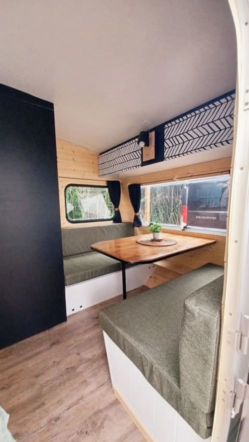 Intérieur chaleureux du cottage La Cour d'Hortense avec espace assis en bois, table à manger et vue sur le jardin par les fenêtres
