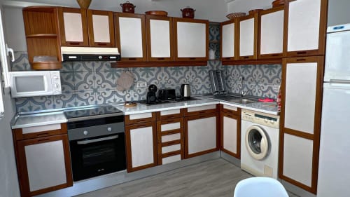 Cocina moderna con muebles de madera, azulejos decorados y electrodomésticos de acero inoxidable en Casa Torrens, Polop de la Marina