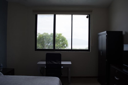 Habitación del Hotel El Candelero en Yuriria con escritorio, silla y ventana con vistas al paisaje verde
