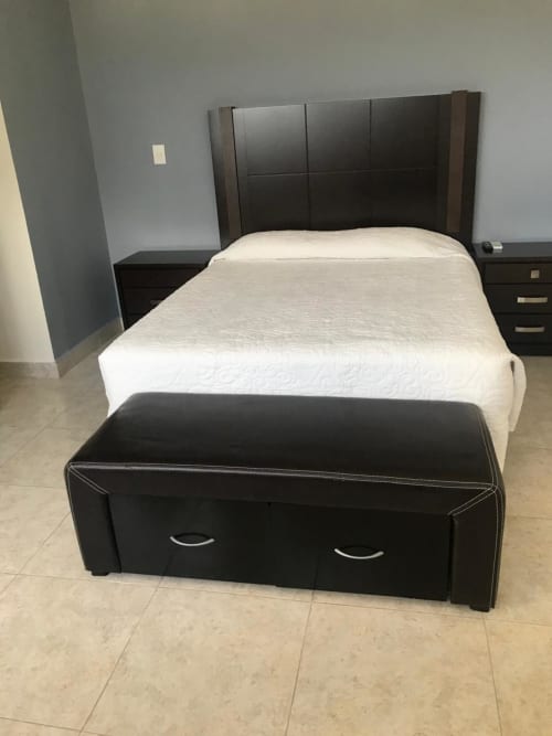 Habitación moderna del Hotel El Candelero con cama tapizada en negro, ropa de cama blanca y banco de almacenaje en Yuriria